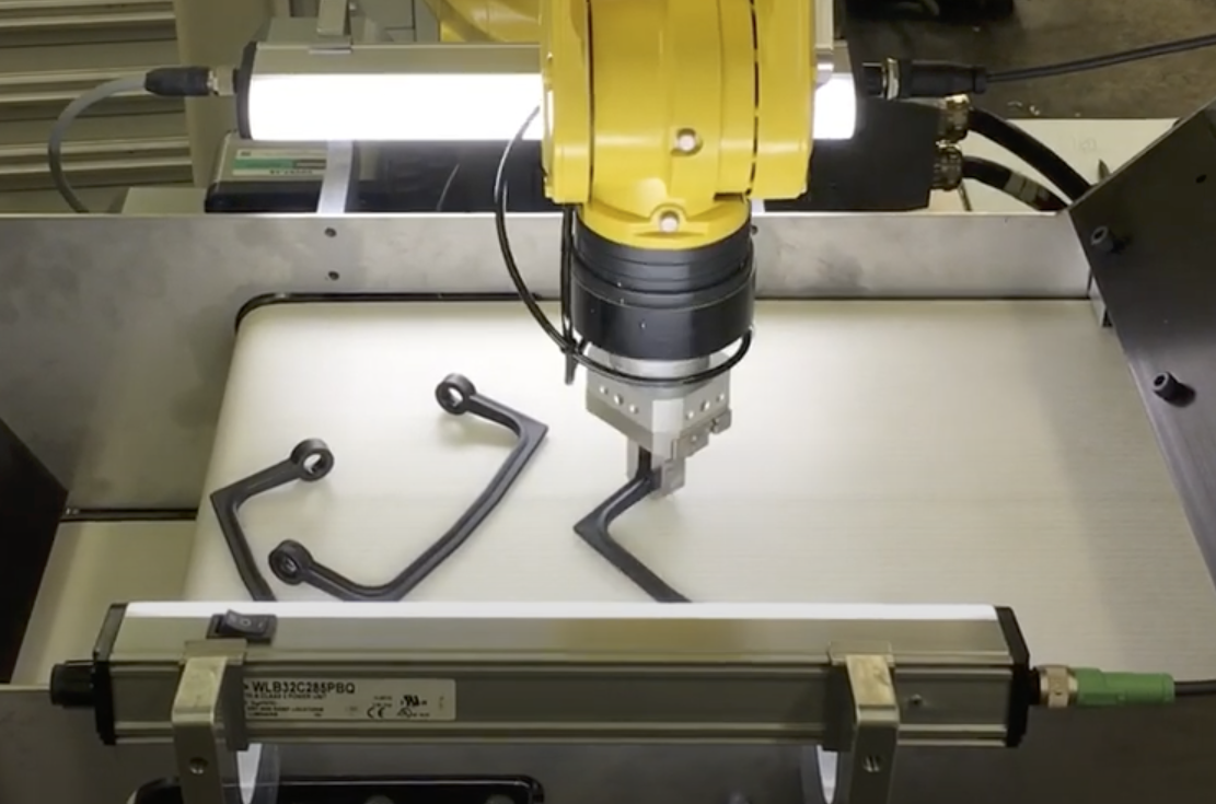 automated robotic arm picking parts from a conveyor feeder