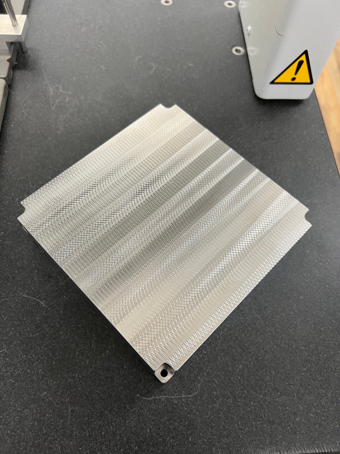 A build plate lying flat with lines of grooves
