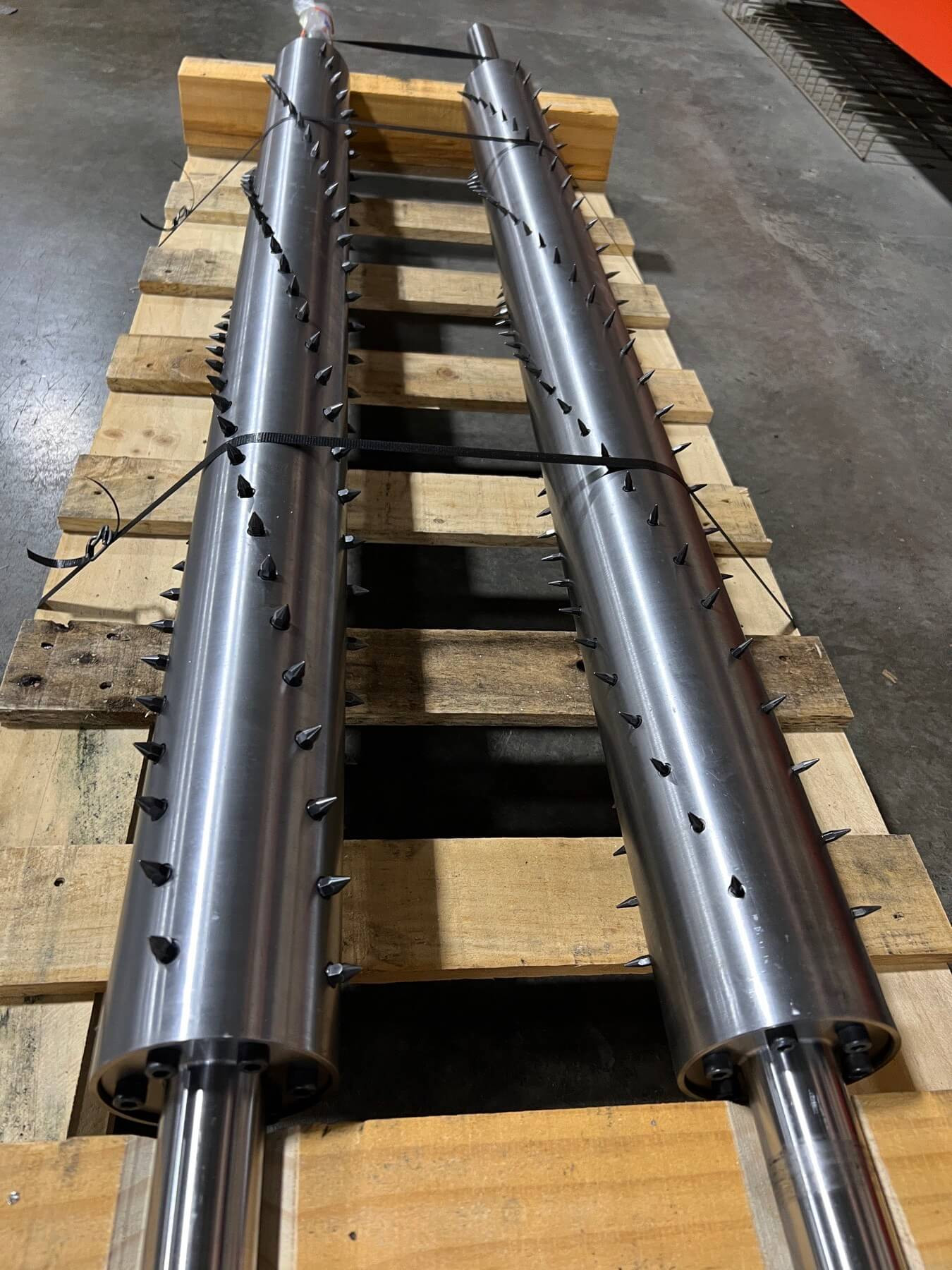 Two roll shafts with spikes for perforation lying on a wooden pallet